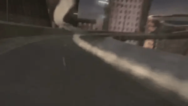 A French bulldog in an olive hoodie and black track pants rides the invisible motorbike straight at the camera with its tongue out